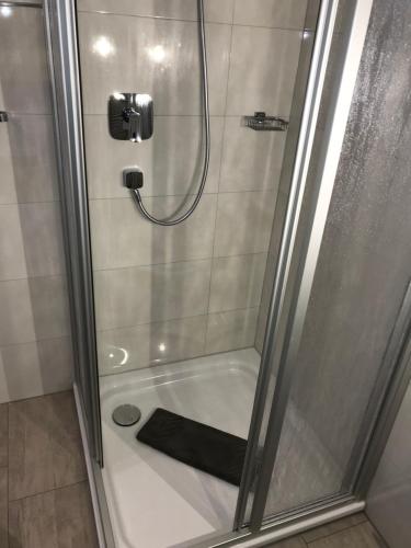 a shower with a glass door with a black towel at Pension Villa Transvaal in Ahlbeck