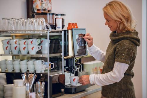 a woman is making a cup of coffee at Rittis Alpin Chalets Dachstein in Ramsau am Dachstein