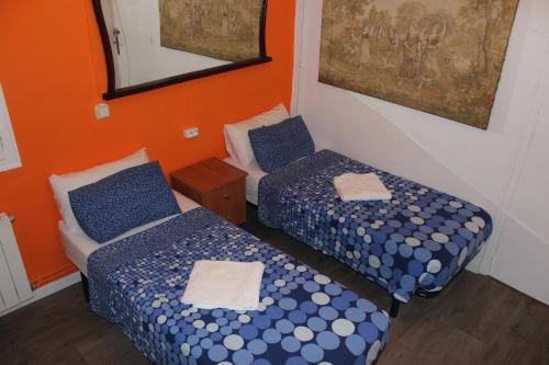 two twin beds in a room with orange walls at Pensión Arosa in Barcelona