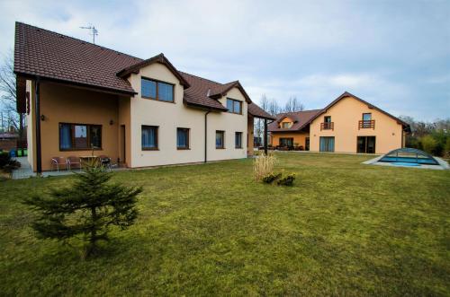 a house with a yard with a tree in front of it at Penzion Na Americe in Nové Jirny
