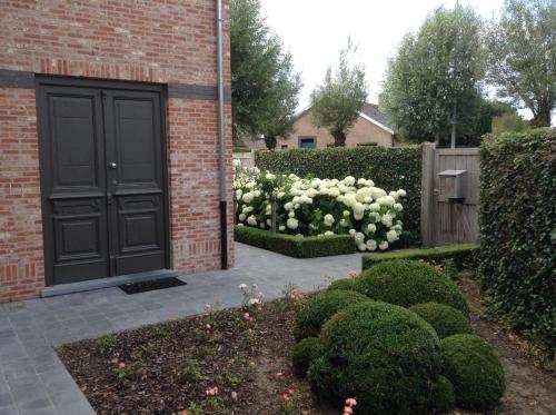 a brick house with a black door and white bushes at 'Southfield': Stylish & Quiet in Bruges in Bruges
