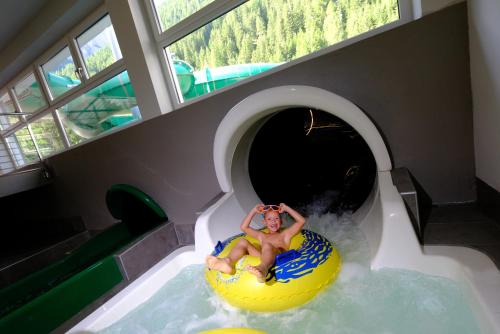 een man die op een vlot van een waterglijbaan afglijdt bij Vidor Resort in Pozza di Fassa
