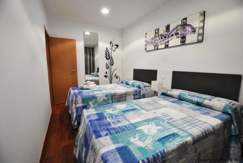 Habitación de hotel con 2 camas y espejo en Apartamentos Hemar Granada, en Granada