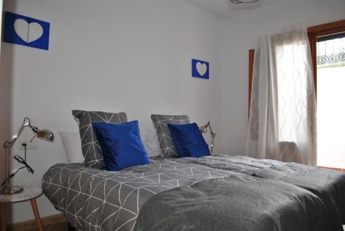 a bedroom with a bed with blue pillows and a window at Casa La Plaza in Frigiliana