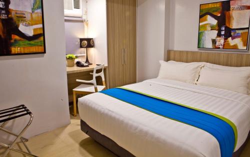 a bedroom with a bed and a desk with a chair at Z Pad Residences in Tacloban