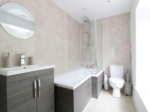 een badkamer met een wastafel, een toilet en een spiegel bij Hillside Cottage in Prestatyn