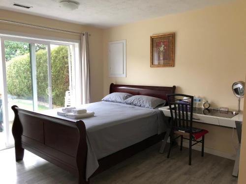 a bedroom with a bed and a chair and a window at YVR Vickie’s Bed and Breakfast in Richmond