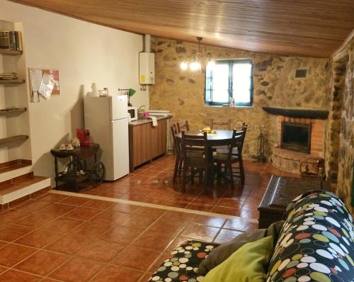 a kitchen and a living room with a table and a refrigerator at Casas da Lagoa - 4 Casas de Férias Independentes in Santo Isidoro