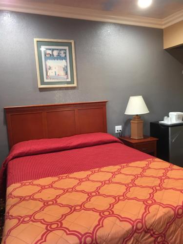 1 dormitorio con 1 cama con colcha roja en Budget Inn LAX-Lawndale, en Lawndale