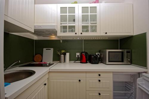 a kitchen with white cabinets and a sink and a microwave at Cozy Gardens Apartments in Prague in Prague
