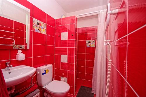 a red bathroom with a toilet and a sink at Cozy Gardens Apartments in Prague in Prague
