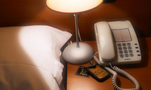 a phone on a table next to a bed at hotel Vajont in Vaiont