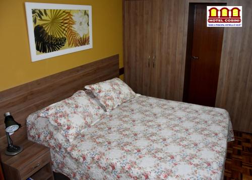 a bedroom with a bed with a floral bedspread at Hotel Cosini in São Sebastião do Paraíso