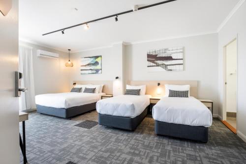 two beds in a room with white walls at Nightcap at Finsbury Hotel in Adelaide