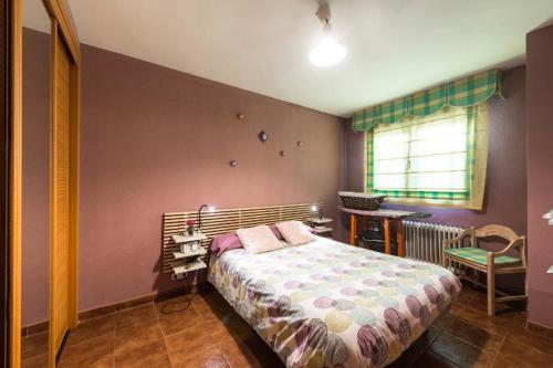 マドリードにあるVivienda Familiar con Jardin junto a Ifemaのベッドとテーブルと窓のある寝室