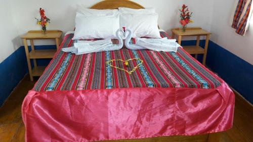 a bed with a pink comforter and towels on it at Amantani Lodge in Amantani