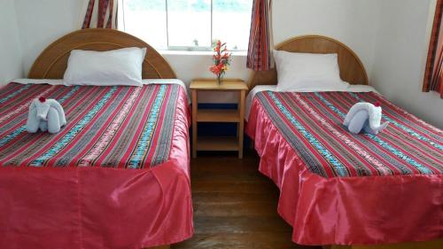 two beds with stuffed animals on them in a room at Amantani Lodge in Amantani
