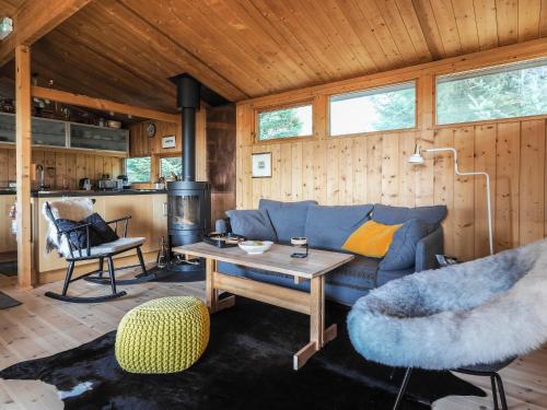 uma sala de estar com um sofá azul e uma mesa em Lovely Cabin in the Capital Area with hot tube em Hafnarfjördur