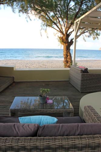 a patio with two couches and a tree on the beach at Effi Apartments in Plataniás