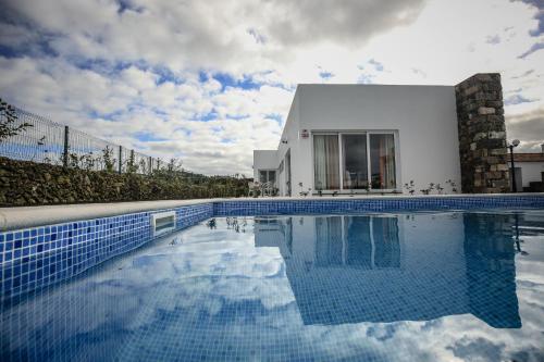 a swimming pool in front of a white house at Quinta das Giestas in Ribeira Grande