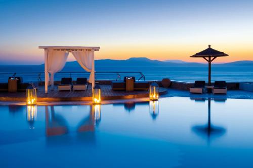 a pool with a wedding set up at sunset at Mykonos Grand Hotel & Resort in Agios Ioannis Mykonos