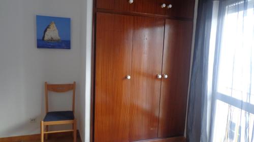 a wooden cabinet with a chair next to a window at Blue Apartment in Portimão