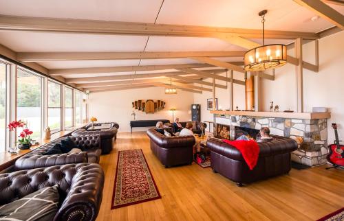 a large living room with leather couches and a fireplace at Pedder Wilderness Lodge in Strathgordon