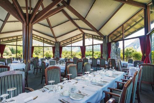 un comedor con mesas y sillas blancas en The Hermitage Hotel Mt Cook en Mount Cook Village