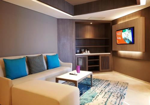 a living room with a couch and a tv at Grand Mercure Jakarta Kemayoran in Jakarta