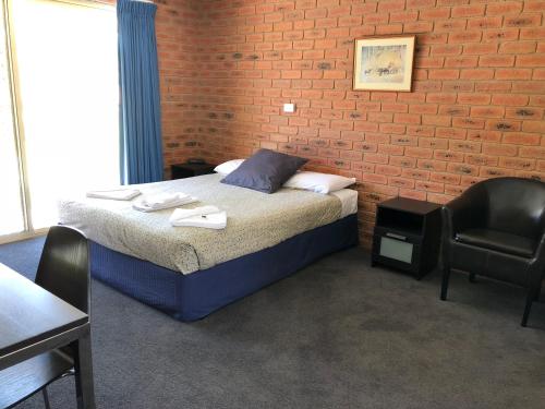 a bedroom with a bed and a brick wall at Bullanginya Lodge in Barooga