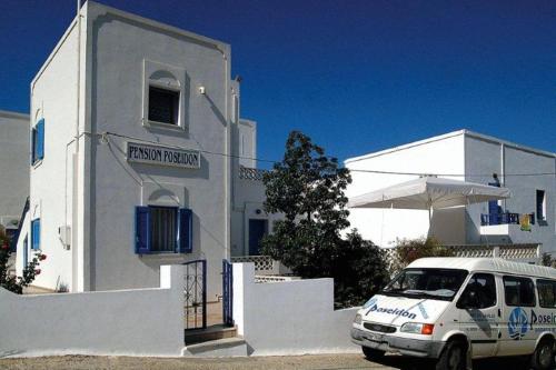 a van parked in front of a white building at Poseidon Studios in Aegiali
