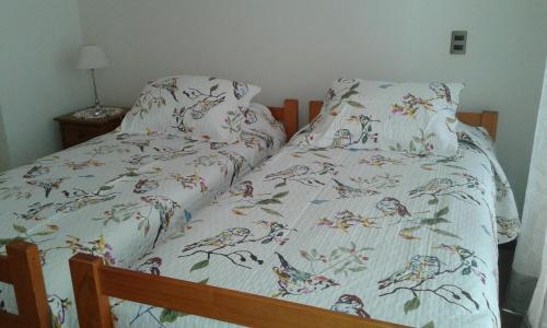 Una cama con un edredón con pájaros. en Departamento Atlántico 4030 en Viña del Mar