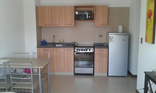 cocina con armarios de madera y nevera blanca en Departamento Atlántico 4030 en Viña del Mar