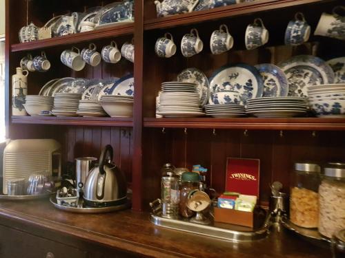 a cabinet filled with plates and bowls and dishes at Blair Athol Homestead in Inverell