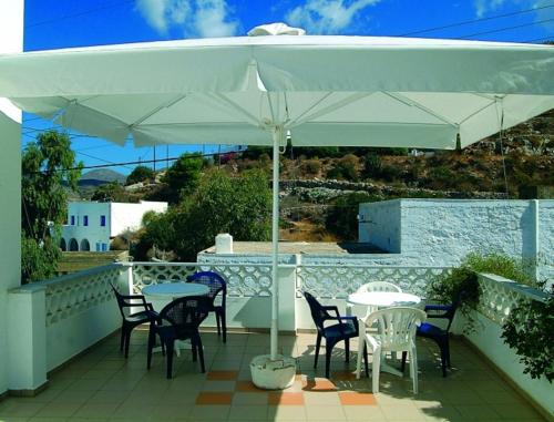 a patio with tables and chairs under an umbrella at Poseidon Studios in Aegiali