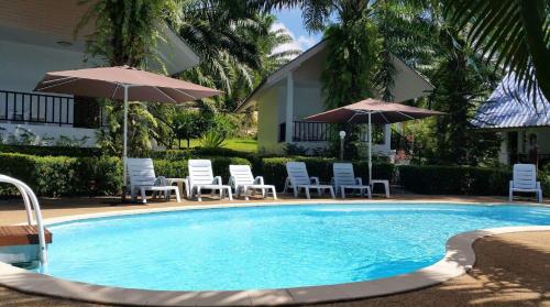 a swimming pool with chairs and umbrellas at Groovy Bungalows in Ao Nang Beach