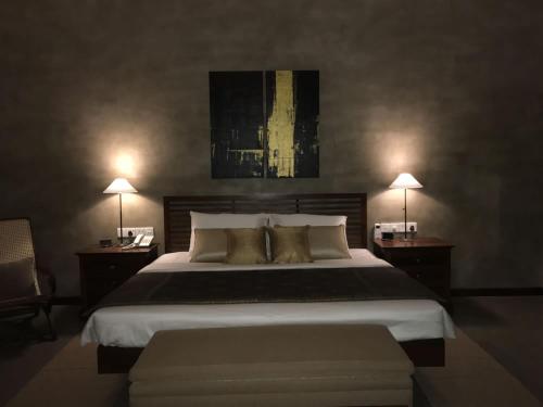 a bedroom with a large bed with two tables and two lamps at Kethaka Aga in Tissamaharama