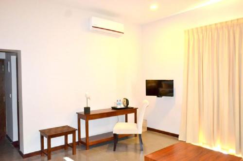 a room with a desk and a chair and a television at Kethaka Aga in Tissamaharama