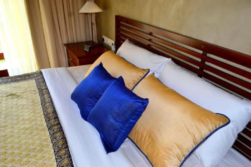 a bed with two blue pillows on top of it at Kethaka Aga in Tissamaharama