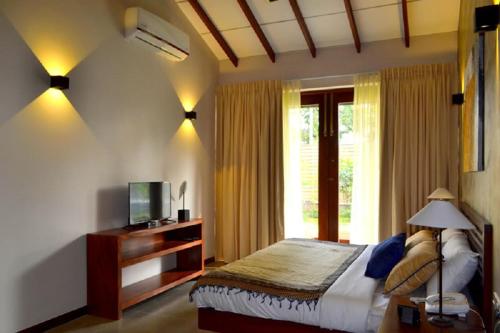 a bedroom with a bed and a tv and a window at Kethaka Aga in Tissamaharama