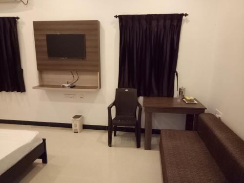 a room with a desk and a table and a television at ComfortWings in Coimbatore