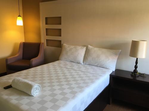 a hotel room with a bed and a chair at Hotel Maiya in San Jose