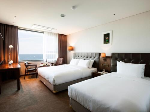 a hotel room with two beds and a desk at Grabel Hotel Jeju in Jeju