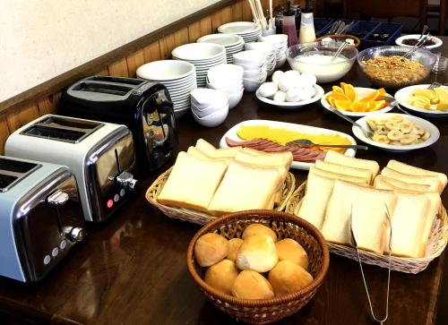 a table topped with baskets of bread and a toaster at Rusutsu Lodges Pension Lilla Huset in Rusutsu