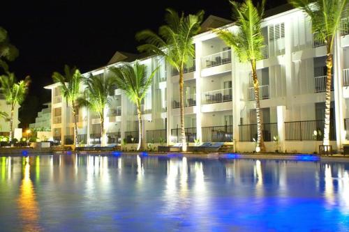 a building with palm trees in front of a pool at Beach Club Port Douglas Luxury Apartments in Port Douglas
