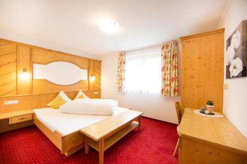 カップルにあるHaus Schöpfのベッドとデスクが備わるホテルルームです。