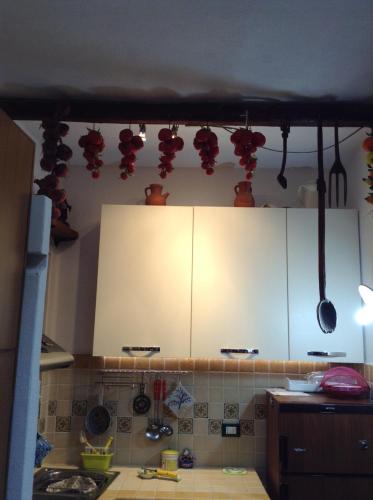 a kitchen with white cabinets and red pots and pans at Residence Vulcano Cottage in Vulcano
