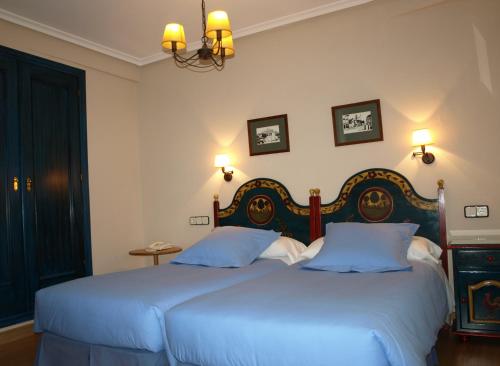 two beds in a bedroom with two blue beds at Hotel Casa Camila in Oviedo