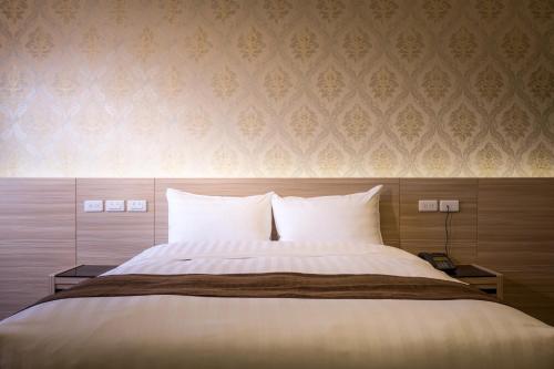 a bedroom with a large bed with white pillows at Hedu Hotel in Beigang