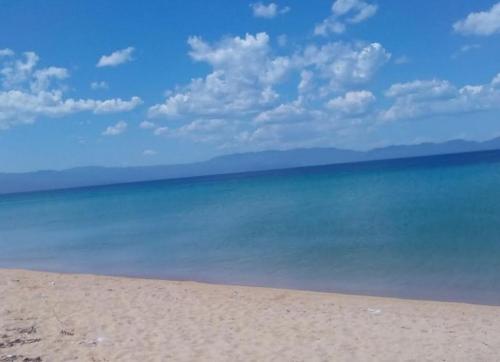 a beach with the ocean and a blue sky and clouds at STONEHOUSE & CASA AL SOLE e AL MARE in Nea Roda